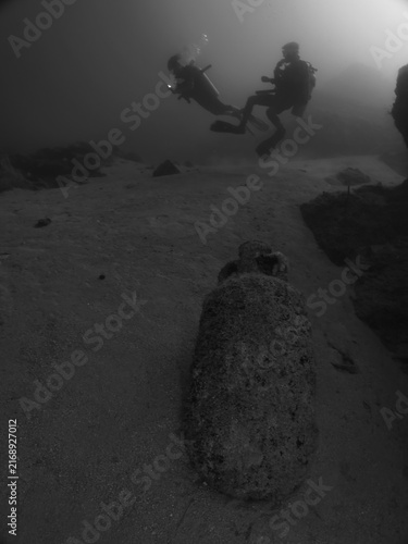 scuba divers are exploring antic old amphoras underwater