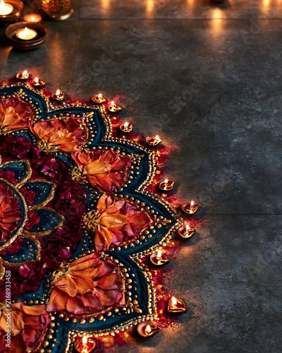 Vibrant flower mandala design with glowing clay lamps on dark surface
