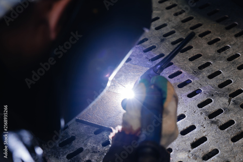 Photography Welder creating arc on perforated metal plate in workshop