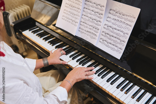 Woman playing piano with sheet music during a private piano class at home