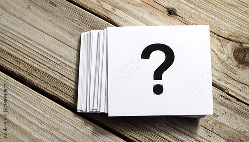 Stack of Square White Paper Cards Printed with Black Question Mark Symbol on Weathered Wooden Surface