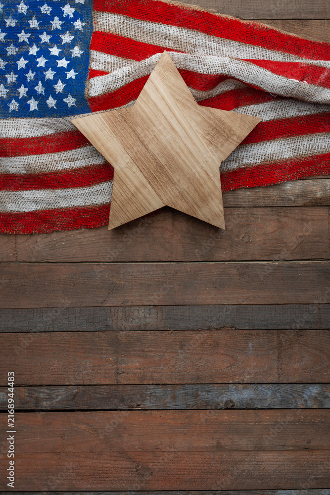 Obraz premium USA flag on burlap with wooden star on rustic wooden background, patriotic composition with copy space for Independence, Flag and Constitution Day design