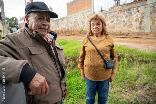 Older couple standing together outdoors in a rural Mexican garden.