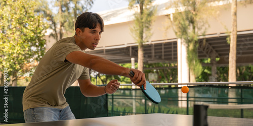 фотографія Young man concentrating while playing outdoor table tennis