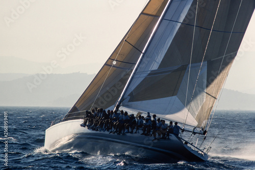 Obraz na plátně Modern racing yacht with full crew hiking out on heeled deck, vintage 35mm film scan