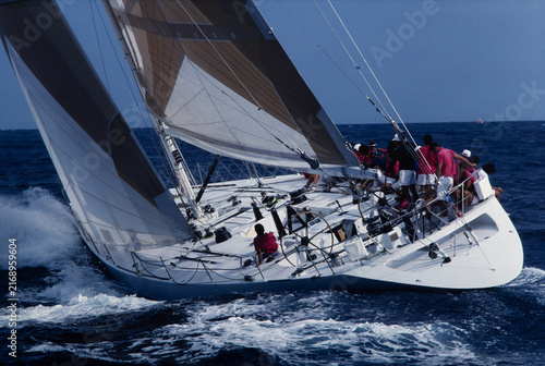 Naklejka Stern perspective of racing yacht heeling steeply in rough seas with crew on rail, vintage 35mm film scan. Teamwork, precision navigation, high performance sailing.