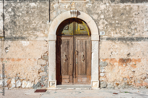 Weathered wooden door on an aged Pirovac building. Croatia
