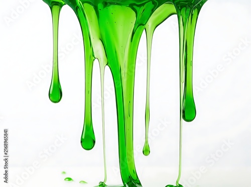 A thick green liquid that appears to be slime or gel is pouring and running downward, producing several droplets on a white background.