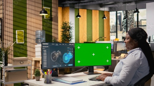 Fotografie Researcher analyzes turbine parts on a chroma key PC while a CAD simulation on an isolated screen computer supports cleaner turbine energy output