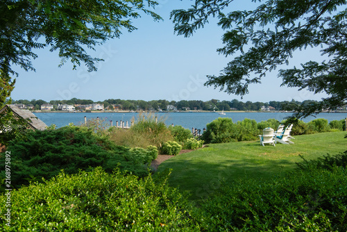Lush green landscaping on a manicured lawn with Adirondack chairs looking out at a waterfront