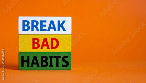 Three stacked colorful wooden blocks with Break Bad Habits text on a wooden surface against an orange background
