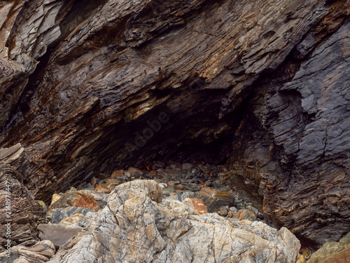 Photography Dark, rugged cave entrance framed by weathered rock layers