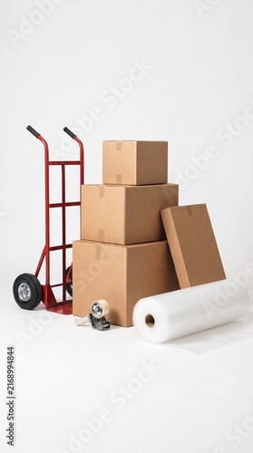 Moving boxes stacked with a hand truck and packing supplies, ready for relocation