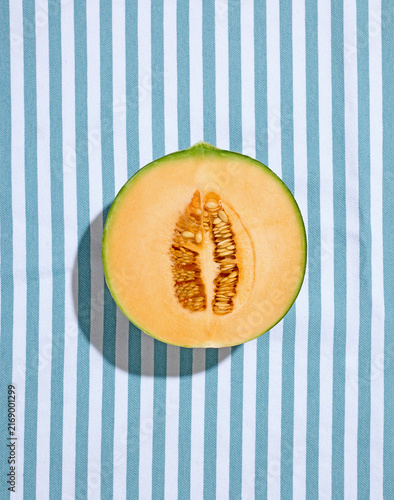 Halved Ripe Melon on Striped Tablecloth in Sunny Light Top View