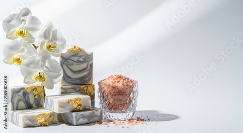 Premium product display with white orchids, gold-leaf marbled soaps, and a clear crystal salt jar against a bright, clean background, shadow, modern, serene