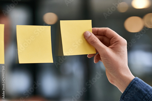 A hand sticking paper notes onto the glass of the company's meeting room