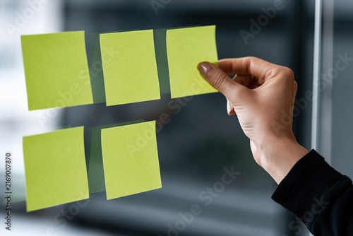 A hand sticking paper notes onto the glass of the company's meeting room