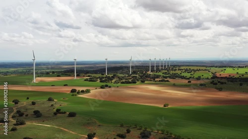 Vast fields stretch endlessly, dotted with spinning wind turbines. Beneath a sprawling sky, nature and technology unite in harmony, revealing the beauty of renewable energy.