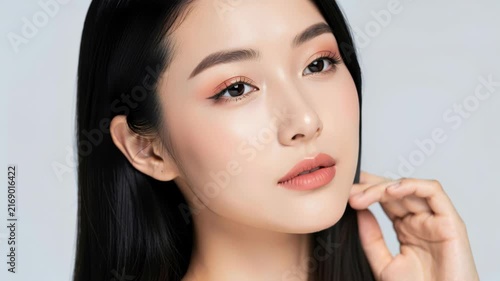 Elegant Asian Beauty: A striking portrait of an Asian woman with flawless skin, expressive eyes, and a gentle smile, showcasing natural makeup and a sophisticated look.
