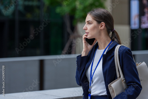 Canvas Print A businesswoman on a mobile call checks a message on her smartphone in the plaza