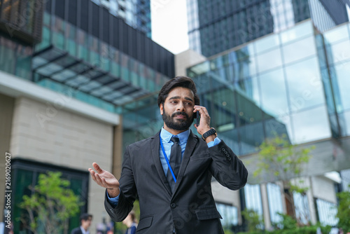 Fotografía A young Indian businessman concentrates on an important call outside the office