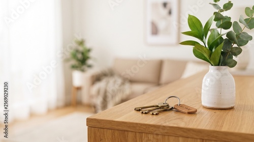 House keys on wooden table with a small plant vase in a cozy bright living room
