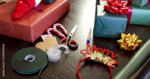 Camera is panning right across table, focusing green gift with gold bow to highlight finished gifts