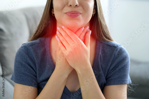 Young woman with hands on neck suffering from sore throat or inflamed tonsils