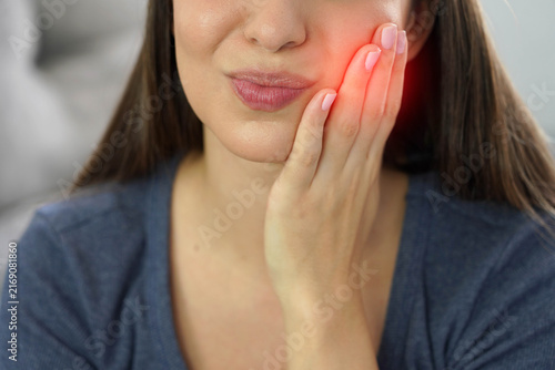 Close up detail of unidentified young woman suffering from toothache with painful face expression