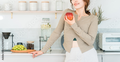 Quadro su tela A woman eating an apple in the kitchen (diet, vegetarian)