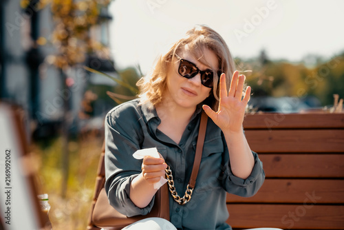 Woman finishing street food spicy meal holding paper napkin showing stop gesture. Mindful eating and portion control concept. Satiated female refusing extra business lunch outdoors.