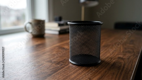 Empty black mesh pen holder on wooden desk