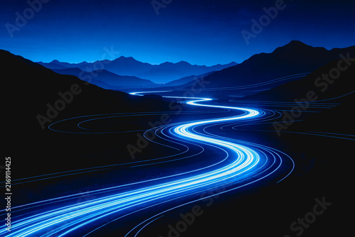 Bright blue glowing light trails curve along a winding road through dark mountainous terrain at night, creating a futuristic visual.