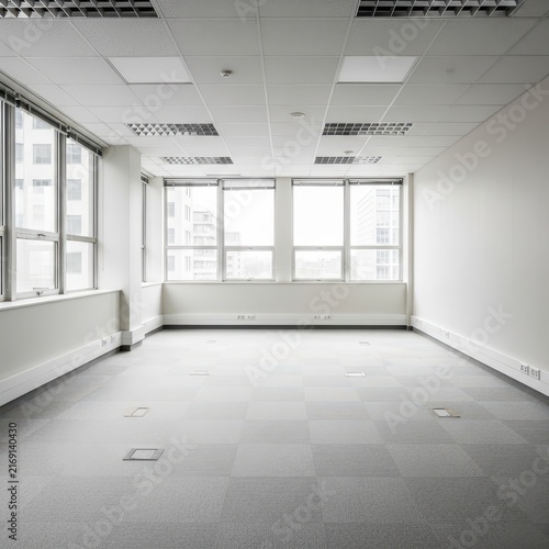Empty modern office space with large windows and white walls.