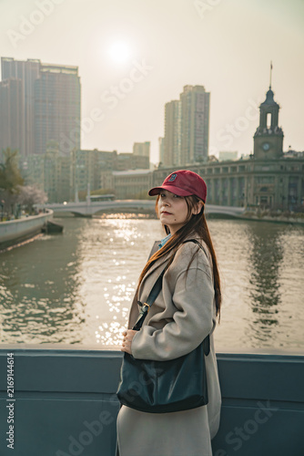 Photography Traveler in a maroon cap looks over her shoulder near a historic clock tower, Zh