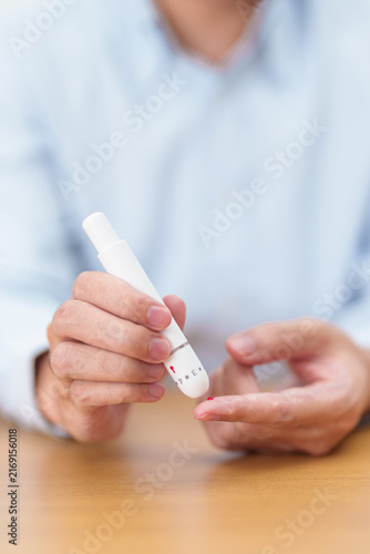 Hand using lancet pen on finger with Blood drop glucose testing or Diabetes checking by digital blood glucose meter. blood sugar level, Diabetes Day, Glycemia, Hypoglycemia, Hyperglycemia and insulin