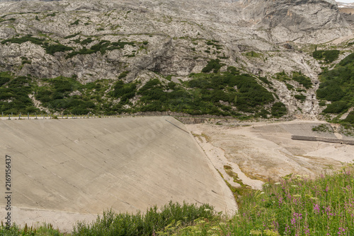 Canazei, Italy. Lago di Fedaia reservoir dam and exposed lakebed showing drought and low water levels in the Dolomites