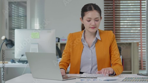 Professional businesswoman calculating finances and typing on laptop