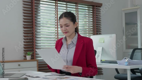 Young businesswoman reading financial report document at her office desk