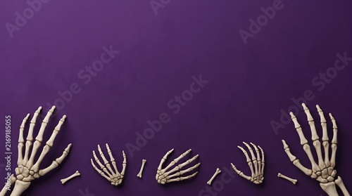 Human skeletal hands and bones lie on a purple backdrop