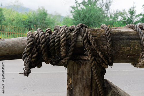 Foto Close up of rustic wooden fence connected with thick natural rope knot for outdoor security and construction concept