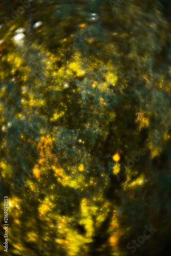 A vertical abstract background featuring a swirling vortex of glowing yellow bokeh light orbs, deep green foliage textures, and golden glittering sparks creating a dreamy, mystical nature backdrop.