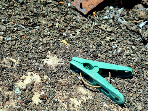 Принти на полотні Old discarded green clothespin on dirt and sand surface