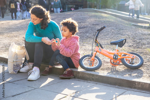 Multiethnic mother and daughter sharing mate in park