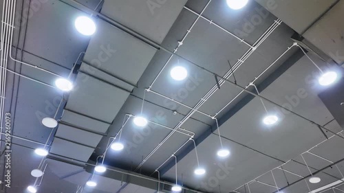 Modern industrial ceiling interior with hanging round LED lights and exposed wiring cables.