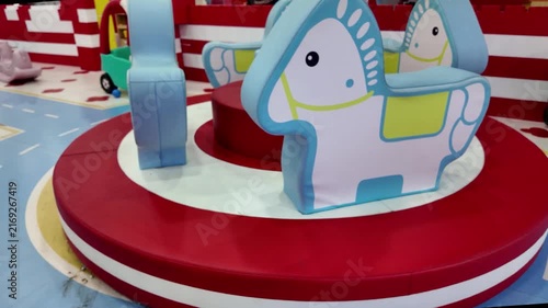 Soft play carousel with cute cartoon horse rides in colorful indoor playground for kids.