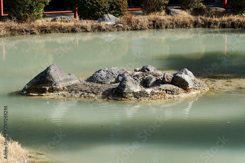 Cuadro en lienzo A small rock island surrounded by calm milky turquoise thermal water in a hot spring pool