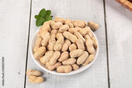 Fotografie Raw Peanuts in Shells on Wooden Background - Healthy Natural Snack Food Ingredie
