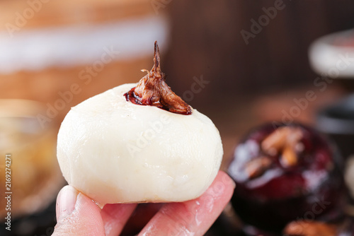 Fresh White Onion with Stem Held in Hand Against Kitchen Background