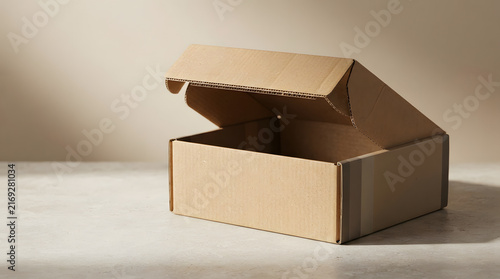 Open empty brown cardboard delivery box on marble surface for shipping packaging logistics or e-commerce retail distribution.